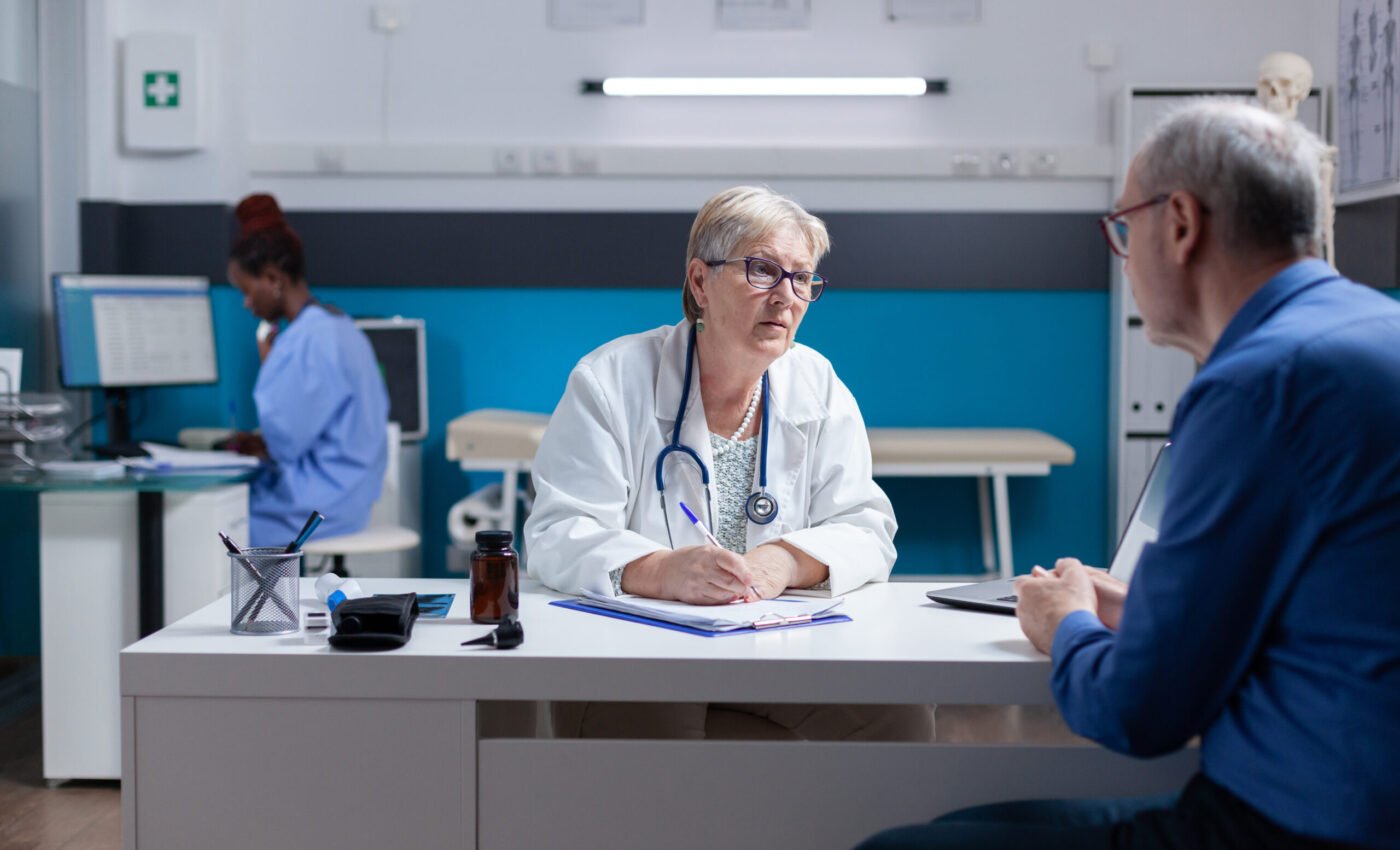 Medic doing signature on checkup papers to give prescription medicine to patient. Woman doctor signing documents after healthcare consultation, giving treatment to senior man with disease.